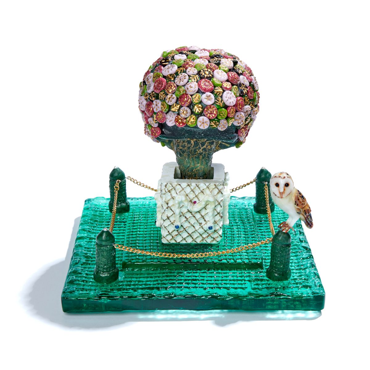 A glass sculpture of a colourful tree with a green base and a Barn owl perched nearby