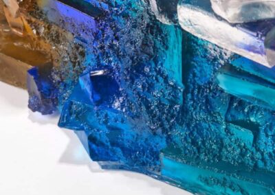 Vivid blue and amber glass sculpture with textured surface, showcasing intricate frozen patterns.